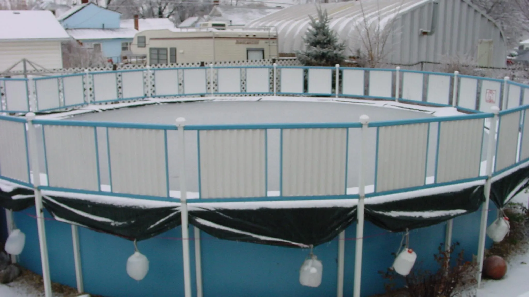 Above-ground pool with its cover drawn across the water, the job a solar reel automates