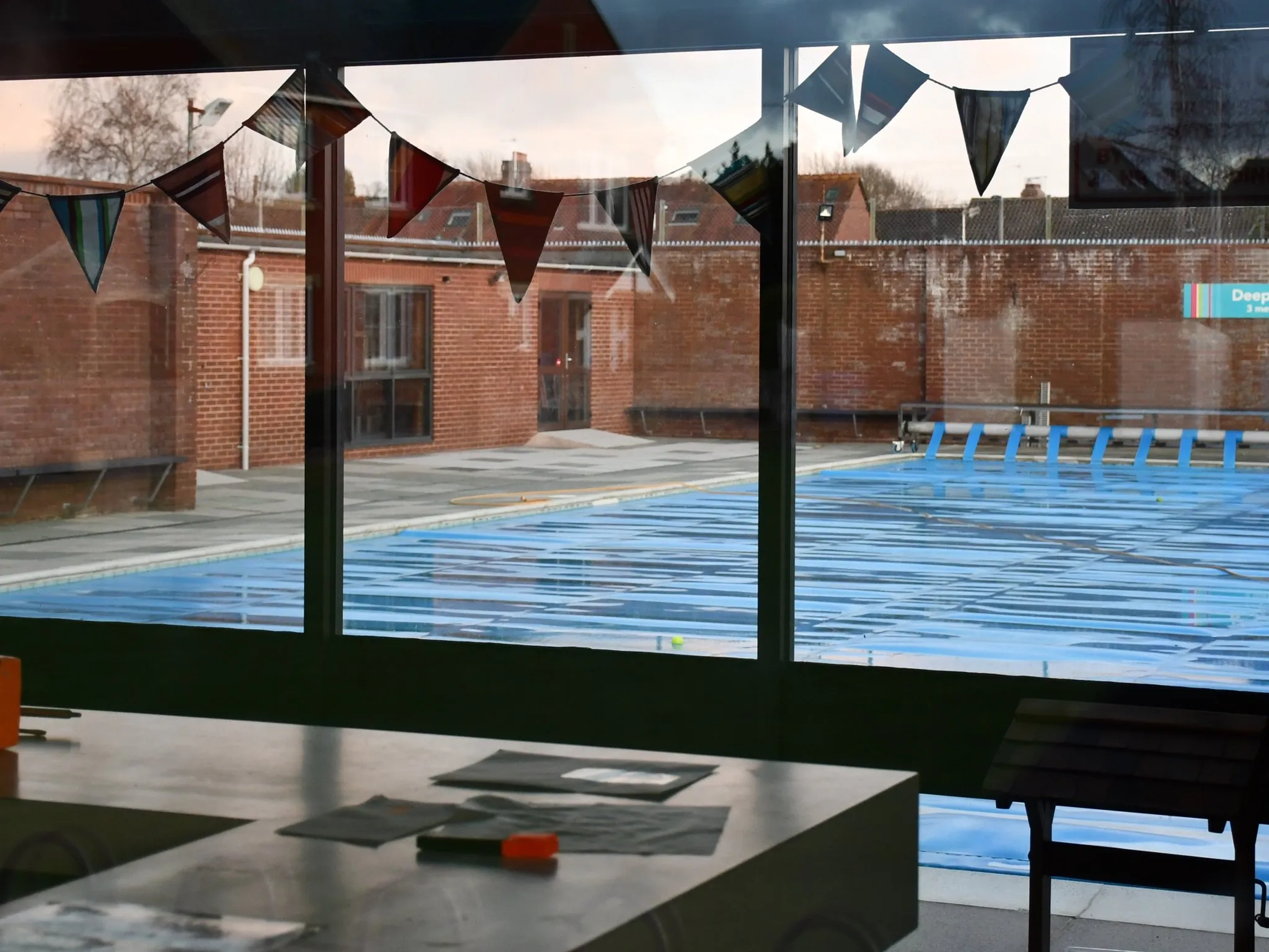 An open-air outdoor swimming pool on a clear day with blue water and a plain surround