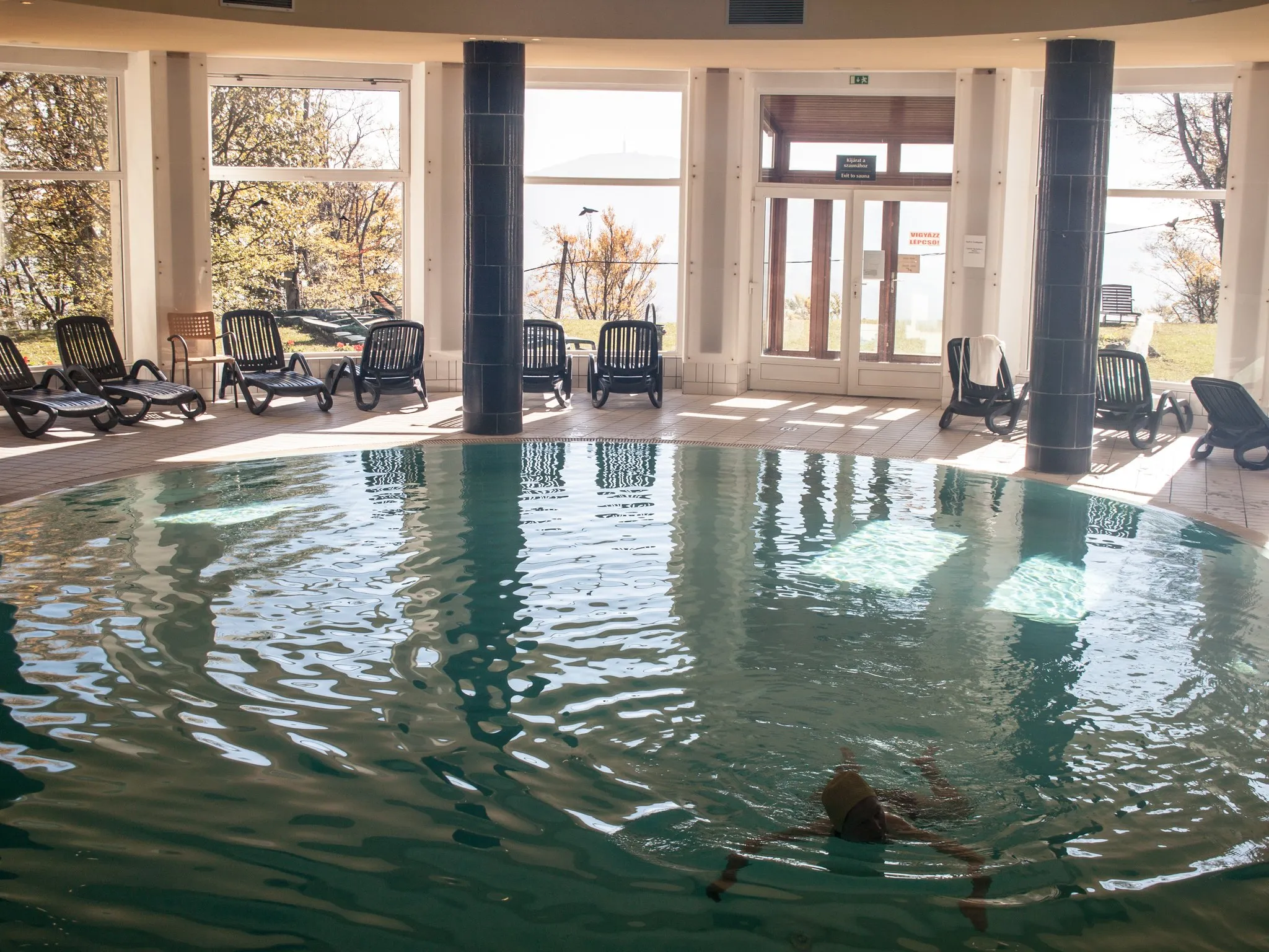 An outdoor hotel swimming pool on a bright day with a sun deck and loungers along the far edge