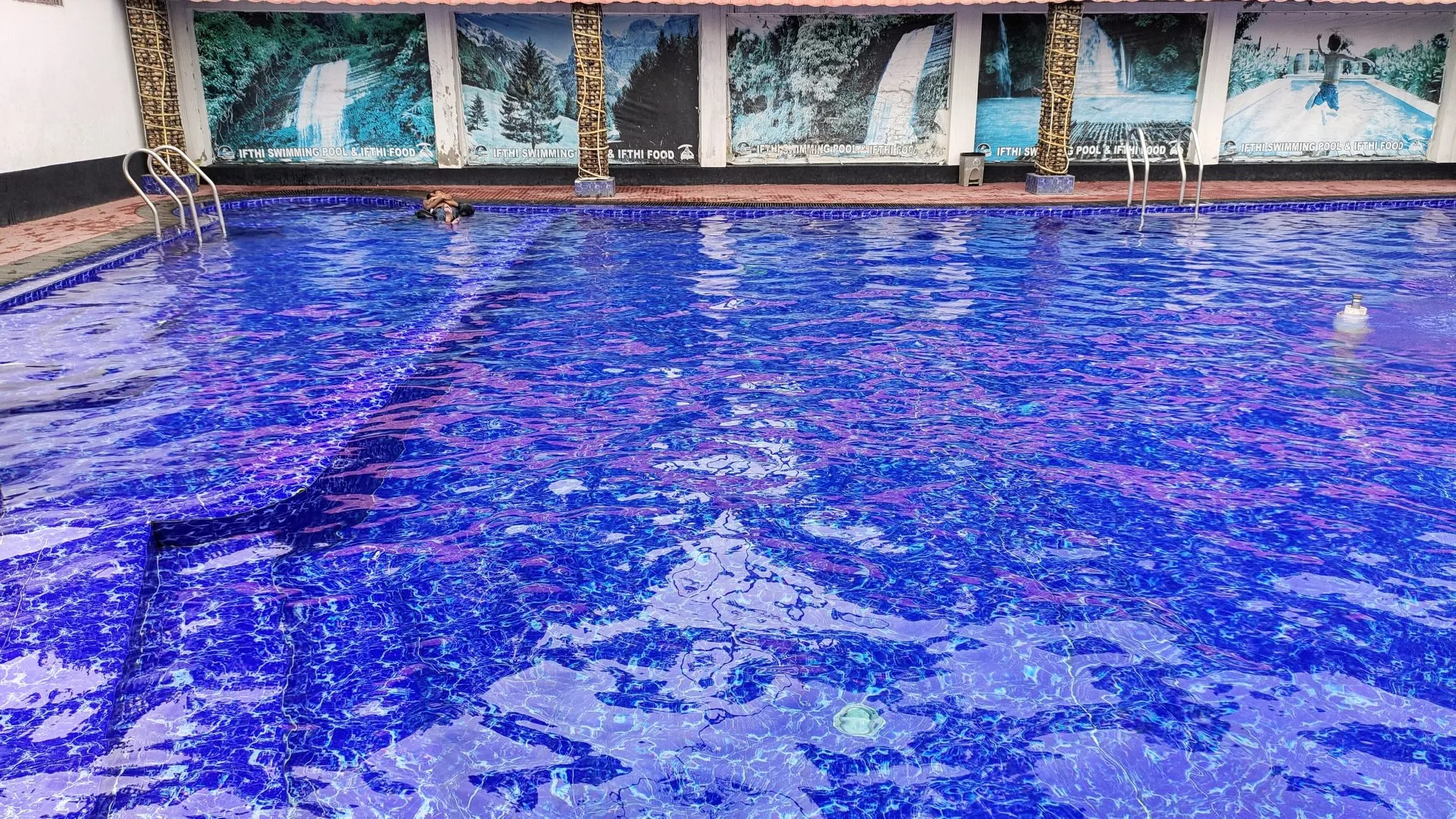 A large in-ground swimming pool with clear turquoise water on a sunny day