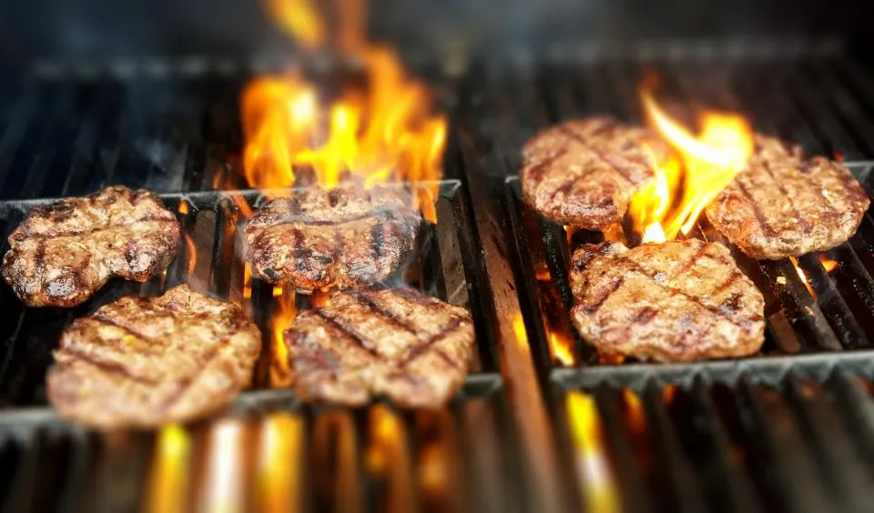 Burgers searing over open flames on a backyard grill